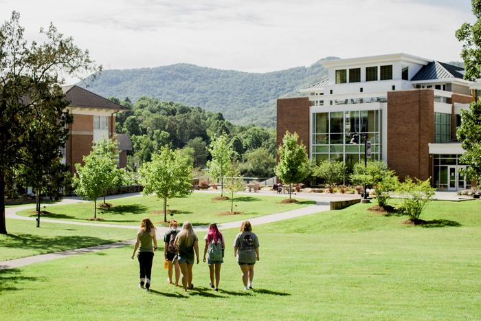 a group of people walking on a path in front of a building